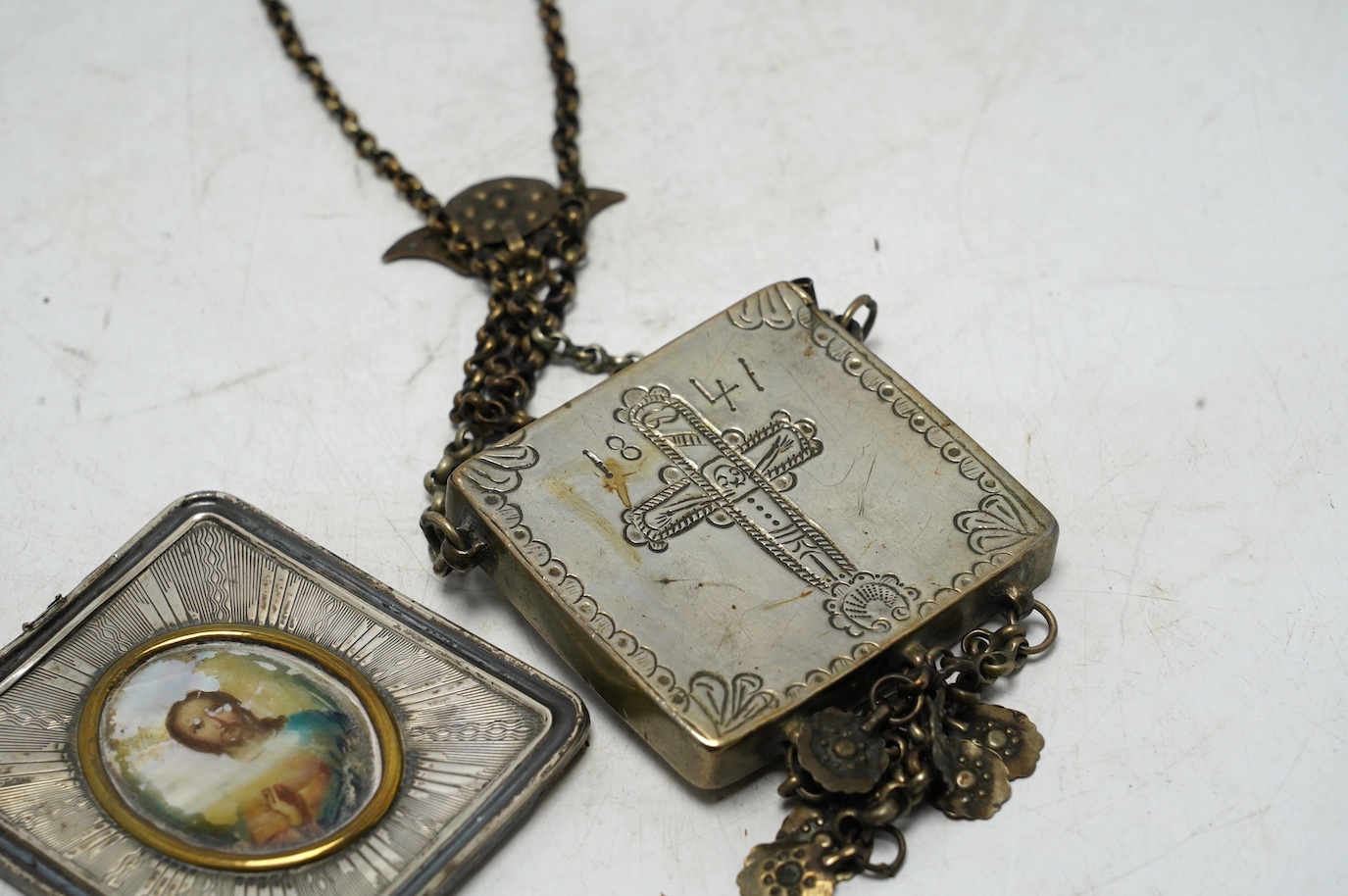 A Greek white metal pendant, embossed with St. George and the dragon, on a chain and a Russian white metal framed portrait of Christ. Condition - poor to fair